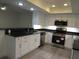 Well-lit kitchen featuring stainless steel appliances, white cabinetry, and black countertops at 7157 Fairway Bend Cir, Sarasota, FL 34243