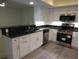 Bright kitchen with white cabinets, stainless steel appliances, and black countertops at 7157 Fairway Bend Cir, Sarasota, FL 34243
