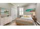 Bedroom with light gray walls, beach-themed art, a white dresser, and a wicker bed frame at 7364 47Th Avenue E Cir, Bradenton, FL 34203