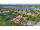 Aerial view of an upscale neighborhood with tile roofs, lush landscaping, and waterfront homes surrounding a lake at 7628 Haddington Cv, Lakewood Ranch, FL 34202