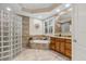 Spa-like bathroom featuring a glass-block shower, a soaking tub, tile finishes, and a wooden vanity at 7628 Haddington Cv, Lakewood Ranch, FL 34202