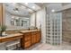 Primary bathroom with granite counters, wood cabinets, tile floor and glass block shower at 7628 Haddington Cv, Lakewood Ranch, FL 34202