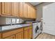 Laundry room with wood cabinets, folding counter, utility sink and washer/dryer at 7628 Haddington Cv, Lakewood Ranch, FL 34202