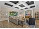 Open-concept living room features a coffered ceiling and opens to a screened patio through sliding glass doors at 7628 Haddington Cv, Lakewood Ranch, FL 34202