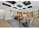 Spacious living room featuring a coffered ceiling with a modern chandelier and views into the kitchen at 7628 Haddington Cv, Lakewood Ranch, FL 34202