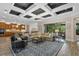 Spacious living room with coffered ceilings, comfortable seating, and seamless access to the outdoor living area at 7628 Haddington Cv, Lakewood Ranch, FL 34202