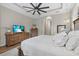 Serene main bedroom with a tray ceiling, dresser with TV, and an ensuite bathroom with a walk-in closet at 7628 Haddington Cv, Lakewood Ranch, FL 34202