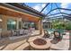 Beautiful covered patio with a fire pit, outdoor seating, and access to the screened-in pool at 7628 Haddington Cv, Lakewood Ranch, FL 34202