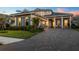 Stunning two-story home with a paved driveway, manicured lawn, and charming architectural details at sunset at 8209 Redonda Loop, Lakewood Ranch, FL 34202