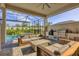 This covered patio features a stone outdoor kitchen with a grill, sink, and comfortable seating area at 8209 Redonda Loop, Lakewood Ranch, FL 34202