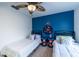 Shared bedroom with twin beds, blue accent wall, and overhead fan at 8709 9Th Nw Ave, Bradenton, FL 34209