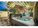 Outdoor hot tub under a pergola with an umbrella, surrounded by tropical landscaping and brick patio at 8709 9Th Nw Ave, Bradenton, FL 34209