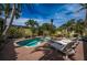 Lush backyard featuring a kidney-shaped pool, surrounded by palm trees, patio, lounge chairs, and privacy fencing at 8709 9Th Nw Ave, Bradenton, FL 34209