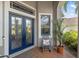 Close-up of a charming entryway with double glass doors, a rocking chair, and a potted palm at 8840 Brookfield Ter, Bradenton, FL 34212
