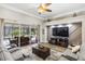 Bright living room with ceiling fan, large-screen TV, and sliding glass doors to screened outdoor dining area at 8840 Brookfield Ter, Bradenton, FL 34212
