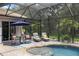 Charming poolside patio with lounge seating surrounded by tropical landscaping and screened enclosure at 8840 Brookfield Ter, Bradenton, FL 34212