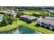 Backyard view of townhome on the pond with a water fountain, green grass, and manicured landscaping at 8979 Milestone Dr, Sarasota, FL 34238