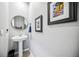 Bathroom with a pedestal sink, round mirror, and framed art enhancing the decor at 8979 Milestone Dr, Sarasota, FL 34238