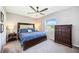 Comfortable bedroom features a large bed, ceiling fan, and dresser with a view to the outdoors at 8979 Milestone Dr, Sarasota, FL 34238