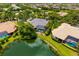 This home features a screened in pool, lake view, lush tropical landscaping, and a luxurious roof at 8999 Wildlife Loop, Sarasota, FL 34238