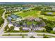 Aerial view of a golf community with lush greenery, lakes, tennis courts, and a stunning clubhouse at 8999 Wildlife Loop, Sarasota, FL 34238