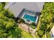 Aerial view of this home's luxurious screened-in pool and patio area, lush landscaping, and stone walkway at 8999 Wildlife Loop, Sarasota, FL 34238