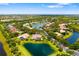 Aerial view of the community showcases a lakefront home surrounded by mature trees and lush landscaping at 8999 Wildlife Loop, Sarasota, FL 34238