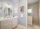 Bathroom with white cabinets, a framed mirror, and tiled walk-in shower at 8999 Wildlife Loop, Sarasota, FL 34238