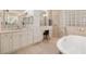 Beautiful bathroom with a standalone tub, travertine tile, glass block wall, and white cabinets at 8999 Wildlife Loop, Sarasota, FL 34238