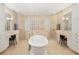 Luxurious bathroom with a standalone tub, glass block wall, dual vanity with makeup area, and travertine tile at 8999 Wildlife Loop, Sarasota, FL 34238