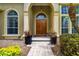Close-up of the front entrance featuring a double door, decorative columns, and colorful potted plants at 8999 Wildlife Loop, Sarasota, FL 34238