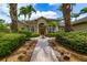 Attractive home exterior with a lush green lawn, mature palm trees, and a brick walkway leading to the front door at 8999 Wildlife Loop, Sarasota, FL 34238