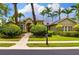 Charming home exterior featuring lush landscaping, mature trees, and a brick walkway leading to the front door at 8999 Wildlife Loop, Sarasota, FL 34238