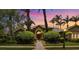 Stunning home exterior with lush landscaping, palm trees, and a beautiful walkway to the front door at sunset at 8999 Wildlife Loop, Sarasota, FL 34238