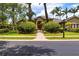 Beautiful front exterior with lush landscaping, a brick walkway, and a well-manicured lawn at 8999 Wildlife Loop, Sarasota, FL 34238