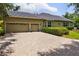 Spacious three-car garage with a brick driveway and beautiful landscaping around the home at 8999 Wildlife Loop, Sarasota, FL 34238