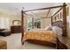 Main bedroom features a four-poster bed, carpet flooring, dresser, and outdoor views at 8999 Wildlife Loop, Sarasota, FL 34238