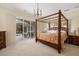 Cozy bedroom boasts a grand four-poster bed, soft lighting, and access to the outdoor pool area at 8999 Wildlife Loop, Sarasota, FL 34238