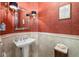 Elegant powder room with unique textured wallpaper, decorative mirror, and pedestal sink at 8999 Wildlife Loop, Sarasota, FL 34238