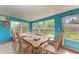 Sunroom dining area with turquoise walls, many windows, and casual table setting at 10095 Nassau Ct, Seminole, FL 33776