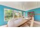 Sunroom dining area with turquoise walls and many windows overlooking an unkept yard at 10095 Nassau Ct, Seminole, FL 33776