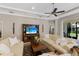 A living room with neutral walls, a ceiling fan, a television, and large windows with curtains at 11610 Griffith Park Ter, Bradenton, FL 34211