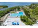 Aerial view of a spacious community pool, surrounded by green landscape, sun loungers, and shaded picnic areas at 1404 Dartmouth Dr, Bradenton, FL 34207