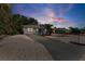 Quaint one-story home with a driveway and rock landscaping, complimented by lush, mature trees at sunset at 1404 Dartmouth Dr, Bradenton, FL 34207