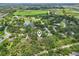 Tranquil aerial view of a house nestled among mature trees with a pond and green space in the background at 1509 Shadow Ridge Cir, Sarasota, FL 34240