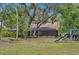 Expansive backyard view with pool, patio, mature trees, and playground at 1509 Shadow Ridge Cir, Sarasota, FL 34240