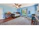 Bright bedroom with blue walls, wooden floors, a ceiling fan, area rug, and desk at 1509 Shadow Ridge Cir, Sarasota, FL 34240