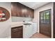 This laundry room features a modern washer and dryer, dark wood cabinetry, and an exterior door at 1509 Shadow Ridge Cir, Sarasota, FL 34240