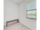 Minimalist bedroom showcasing soft carpet, white walls, and window with bench at 15164 Sunny Day Dr, Bradenton, FL 34211