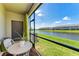 Screened-in patio with woven furniture overlooking tranquil water view and blue skies at 15164 Sunny Day Dr, Bradenton, FL 34211